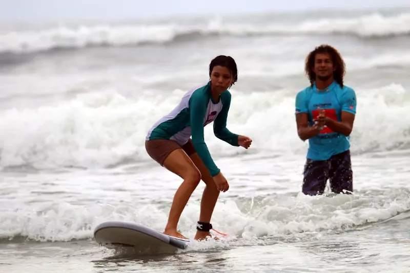 Girl surfing while her instructor is watching