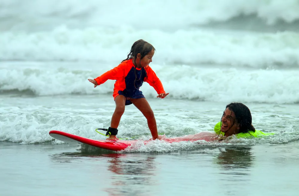 Girl is being pushed while riding a surfboard