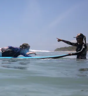 woman surf instructor holds surfboard with student