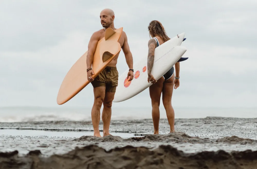 a couple show their fish surfboards at the beach